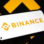 Logo de Binance atrás con el logo de Binance en un teléfono inteligente