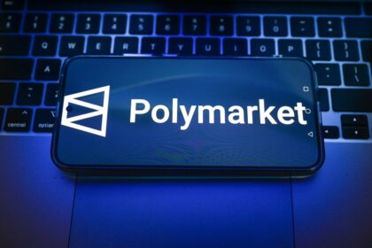 In this photo illustration, a Polymarket logo is displayed on a smartphone on top of a laptop.